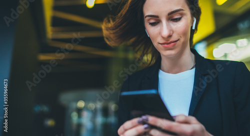 Portrait female entrepreneur in corporate suit using online banking via smartphone. Confident businesswoman texting email letter on cellphone using internet on background modern office