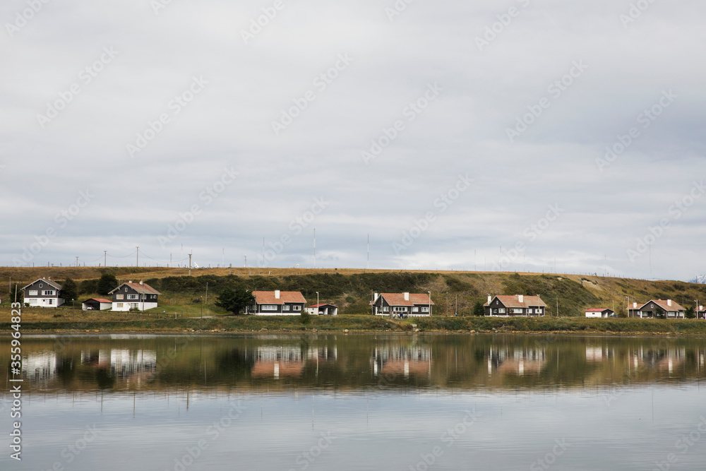 Fototapeta premium Houses in Beagle Channel sea coast, and their perfect reflection in water. Cityscape, Ushuaia.
