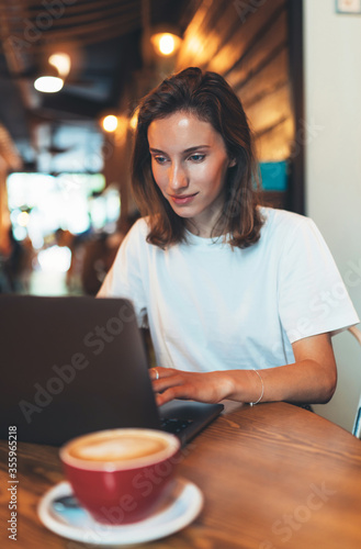 female manager using laptop at cafe workplace with coffee, hipster girl freelancer writing on keyboard, businesswoman working portable computer, education process online internet concept in workspace