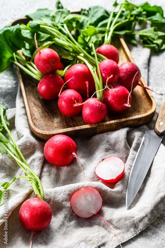 Fresh red radishes in a wooden bowl. Farm organic vegetables. Gray background. Top view