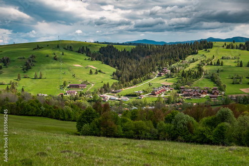 Fototapeta Naklejka Na Ścianę i Meble -  Spring time in beautiful agricultural landscape in the Carpathian mountains. Green farm fields for animals and forest and clouds over the mountains. 