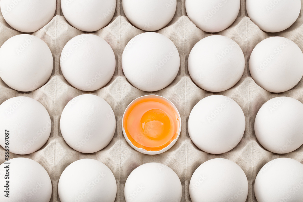 Chicken egg is half broken among other eggs. Top view Chicken egg is half broken among other eggs. Top view