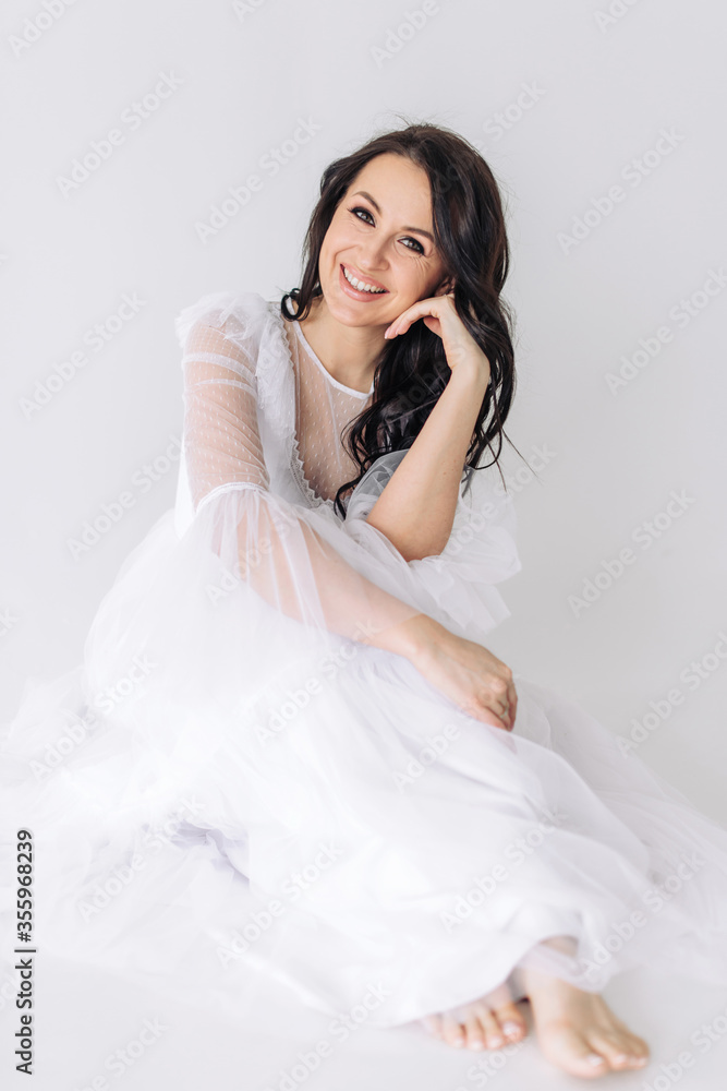 A beautiful and lovely brunette girl with perfect smooth skin and incredible brown eyes in a luxurious white dress smiles a bright and snowy smile. Light and airy vertical photo A beautiful and lovely brunette girl with perfect smooth skin and incredible brown eyes in a luxurious white dress smiles a bright and snowy smile. Light and airy vertical photo