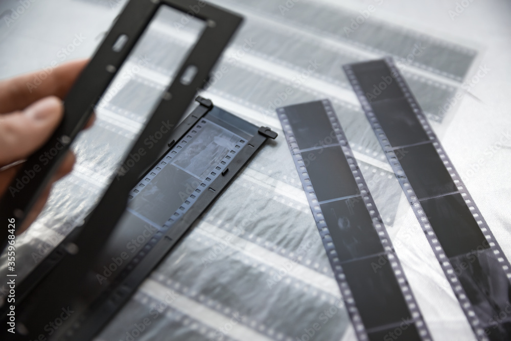 Film photography special envelope slips for negative storage. 35mm and medium format photography. Holding a film strip, putting it inside a scanner frame, preparing for scanning.