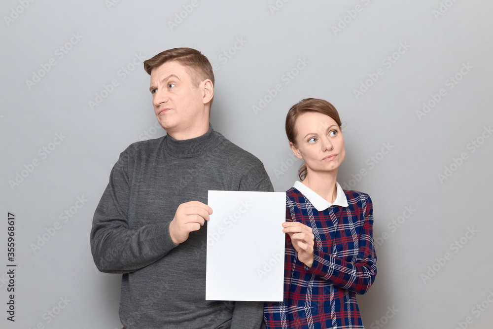 Portrait of adult couple holding together white blank paper sheet Portrait of adult couple holding together white blank paper sheet