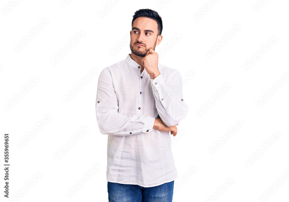 Young handsome man wearing casual clothes serious face thinking about question with hand on chin, thoughtful about confusing idea Young handsome man wearing casual clothes serious face thinking about question with hand on chin, thoughtful about confusing idea