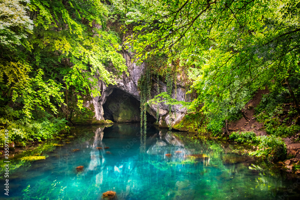 Pond on wellhead of river surrounded with forest and cave on Krupajsko vrelo in Serbia. Beautiful turquoise water.