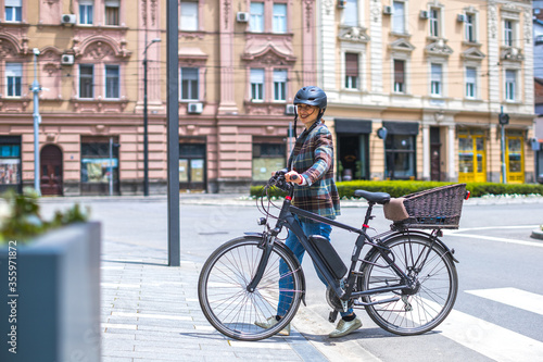 young woman pushing her e-bike on pedestrian walkway