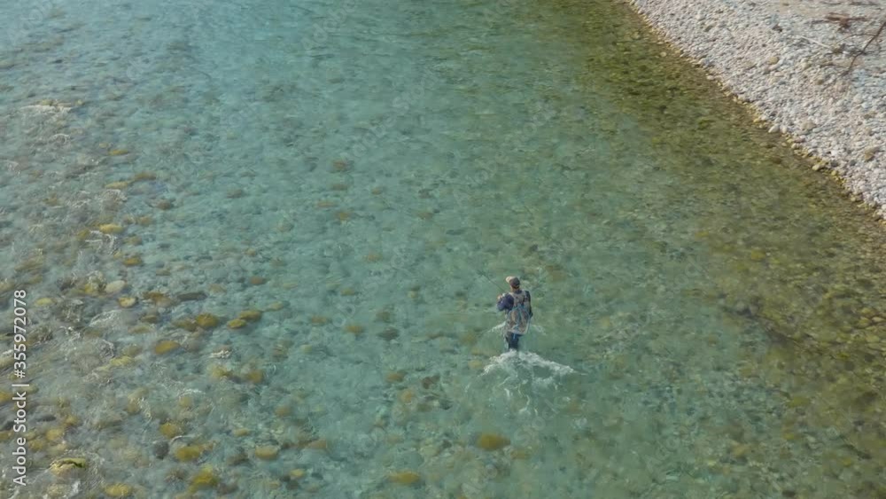 Top shot of a fisherman using the flyfishing technique to cast trout from a river Top shot of a fisherman using the flyfishing technique to cast trout from a river