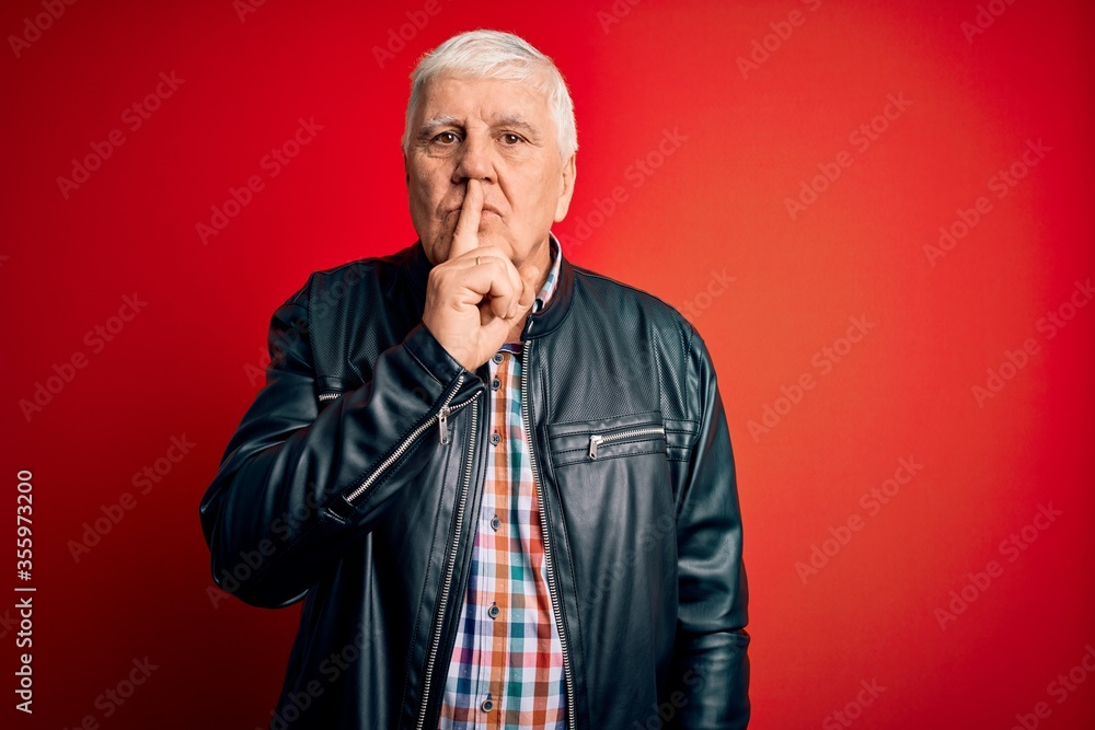Senior handsome hoary man wearing casual shirt and jacket over isolated red background asking to be quiet with finger on lips. Silence and secret concept.