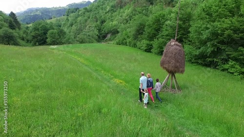 Spodnja Idrija, Slovenia - May 11, 2015: A young family with two children walks across a meadow past a haystack photo