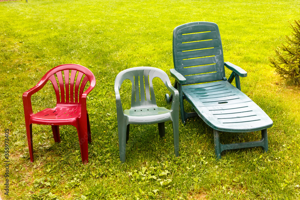 Wet plastic chairs stand on the green grass after the rain. Wet plastic chairs stand on the green grass after the rain.