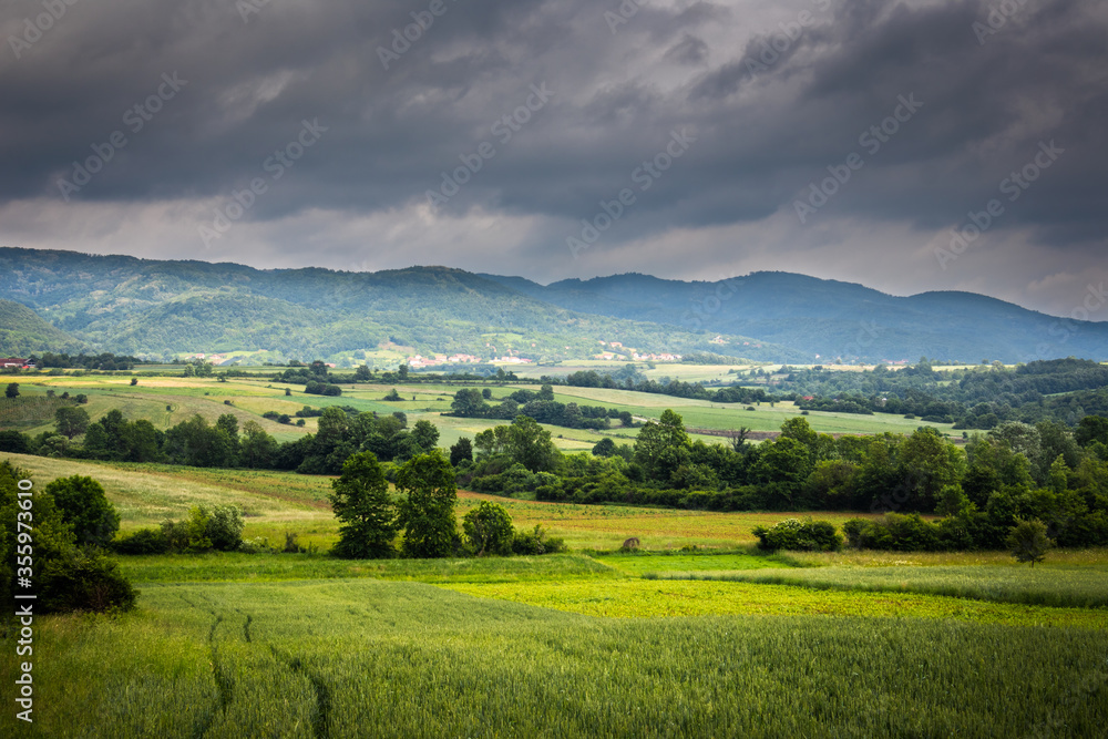 Agriculture field at sunset and dark clouds in spring