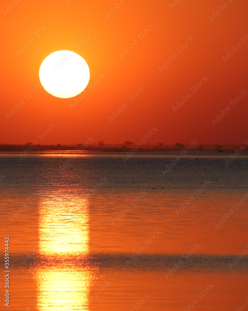 Sunset over the Paraná River in the city of Três Fronteiras, State of São Paulo, Brazil. Beautiful golden and red sunset with a large sun highlighted.