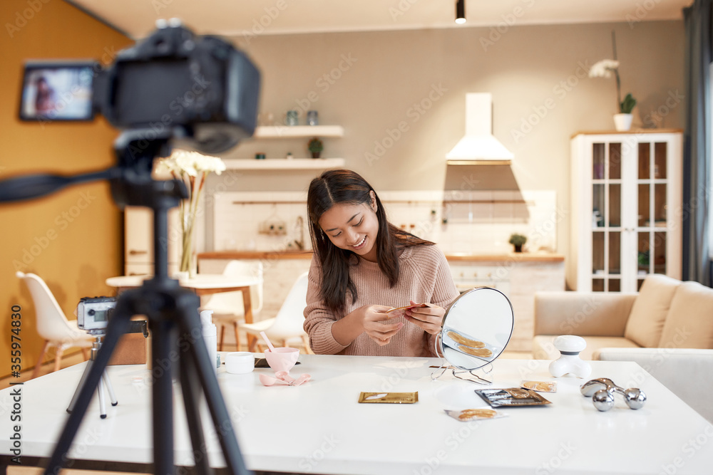 Frame your social space. Young female blogger recording a tutorial video for her beauty blog about skincare routine. Vlogger testing eye patch, recording video for social network Frame your social space. Young female blogger recording a tutorial video for her beauty blog about skincare routine. Vlogger testing eye patch, recording video for social network
