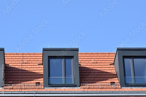 Red roof tiles and dark windows against a blue sky