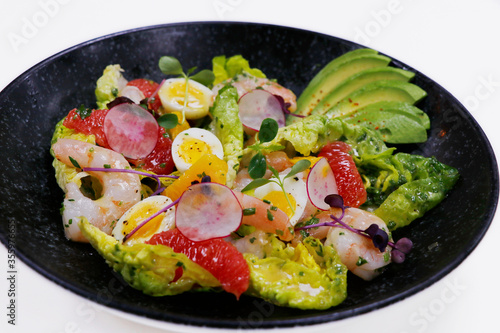 salad with avocado and shrimps in bowl, top view, copy space, black background