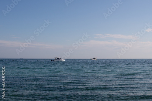 Two white boats navigating towards each other in the sea on a summer day
