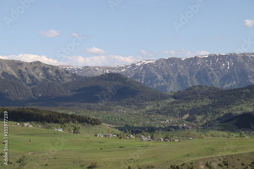 Scenic panoramic landscape of a picturesque green mountain valley in spring. Historic village with blossoming trees and traditional houses.Savsat/ARTVİN/TURKEY