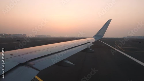 View out of an airplanes right side window while taxiing on Abu Dhabi International Airport during sunset with the terminal buildings and hangars in the background. photo