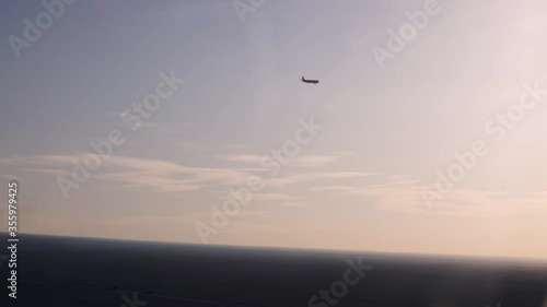 View out of an airplanes left side window seing another aircraft nearby flying the same direction in sunset. photo