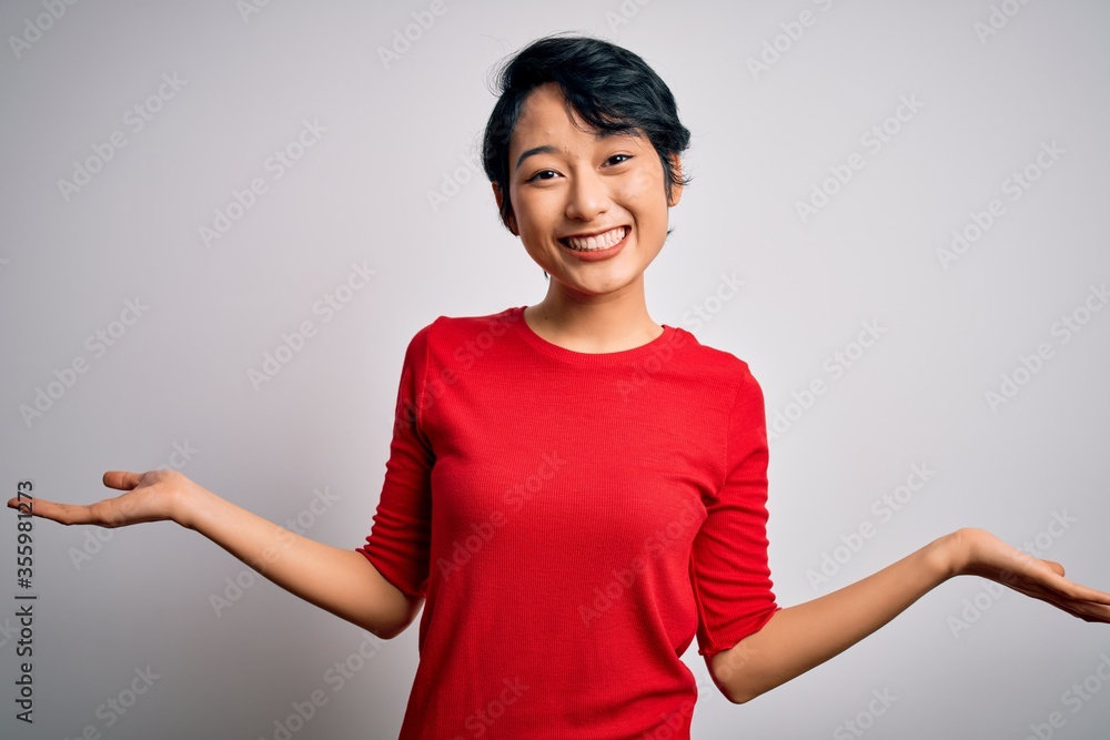 Young beautiful asian girl wearing casual red t-shirt standing over isolated white background smiling showing both hands open palms, presenting and advertising comparison and balance Young beautiful asian girl wearing casual red t-shirt standing over isolated white background smiling showing both hands open palms, presenting and advertising comparison and balance