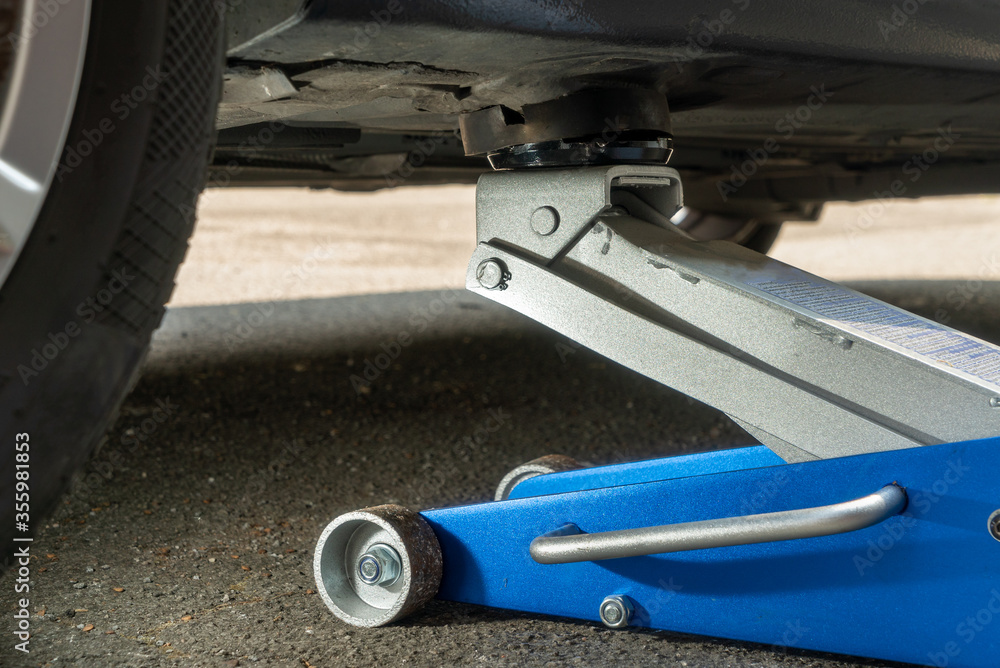 Modern hydraulic jack under a car Modern hydraulic jack under a car