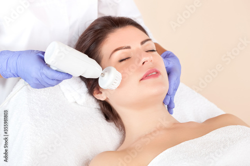 Hardware face cleaning  procedure with a soft rotating brush of a beautiful woman in a beauty salon. Cosmetology and professional skin care. photo