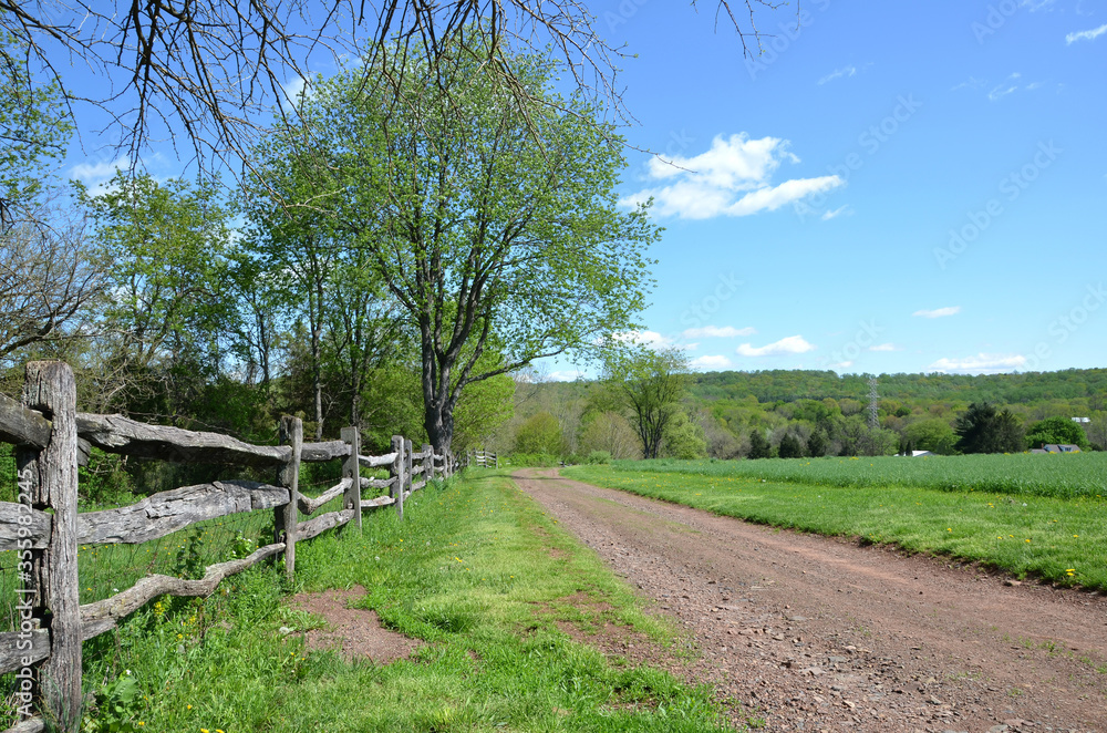 Old dirt country road with a wooden fence.