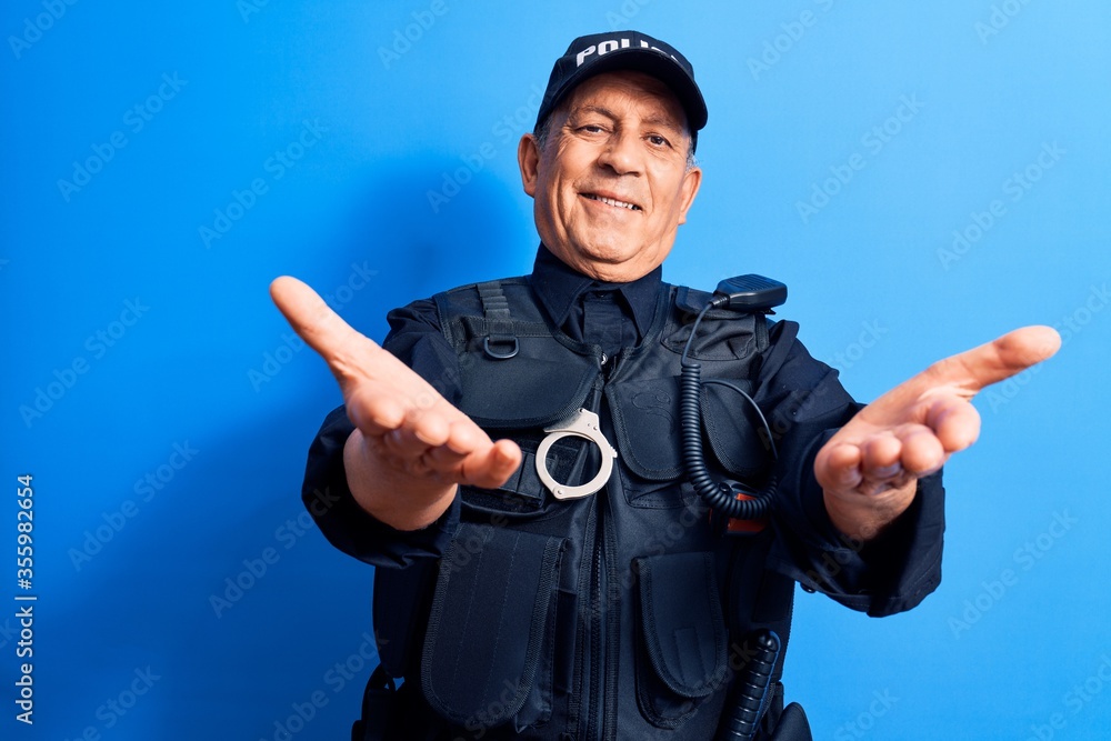 Senior man with grey hair wearing police uniform looking at the camera smiling with open arms for hug. cheerful expression embracing happiness. Senior man with grey hair wearing police uniform looking at the camera smiling with open arms for hug. cheerful expression embracing happiness.