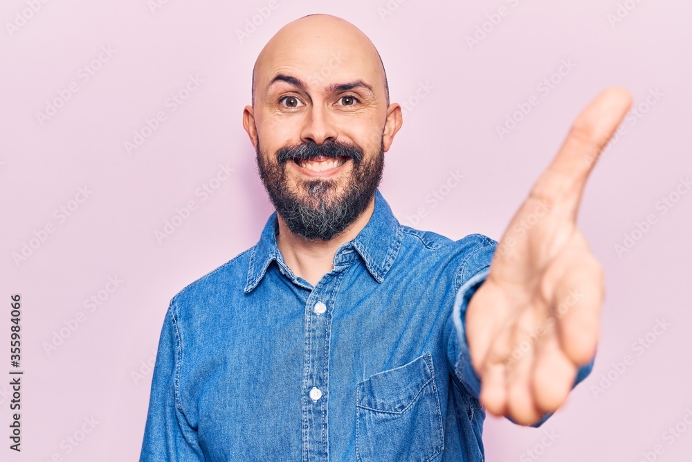 Fototapeta premium Young handsome man wearing casual clothes smiling friendly offering handshake as greeting and welcoming. successful business.