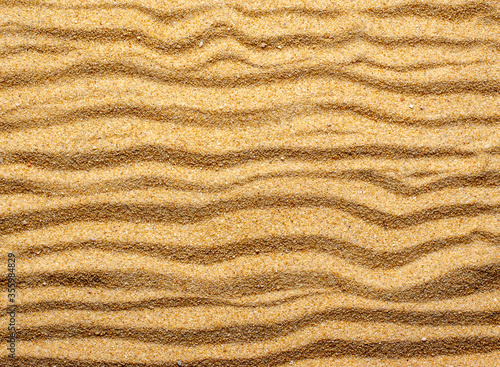 Wave shaped lines on beach sand, close-up. Beach sand texture.
