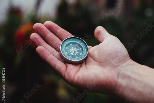 a guy holding a gray compass in a garden