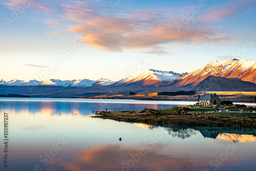 A dusting of snow on the peaks of the Southern Alps surrounding a still Lake Tekapo and the iconic church on the shore