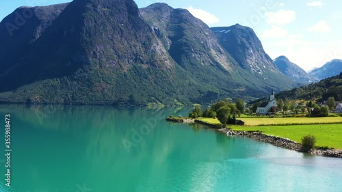 Aerial view on a blue lake with some houses on the beach. Landscape with a drone. Blue lakes, islands, and green forests from above on a cloudy summer morning 