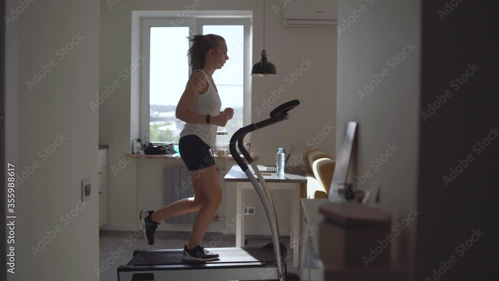 Woman running on running machine at home Woman running on running machine at home