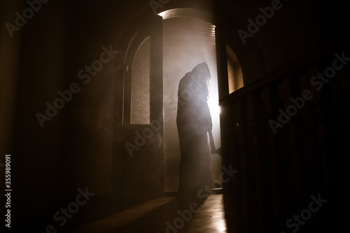 Silhouette of an unknown shadow figure on a door through a closed glass door. The silhouette of a human in front of a window at night. Scary scene halloween concept of blurred silhouette of maniac.