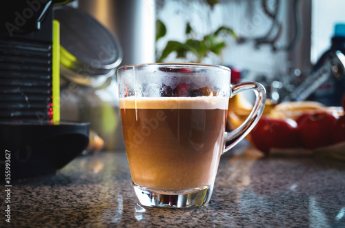 A cup of coffee with milk over a kitchen table. Afternoon coffee time mood.