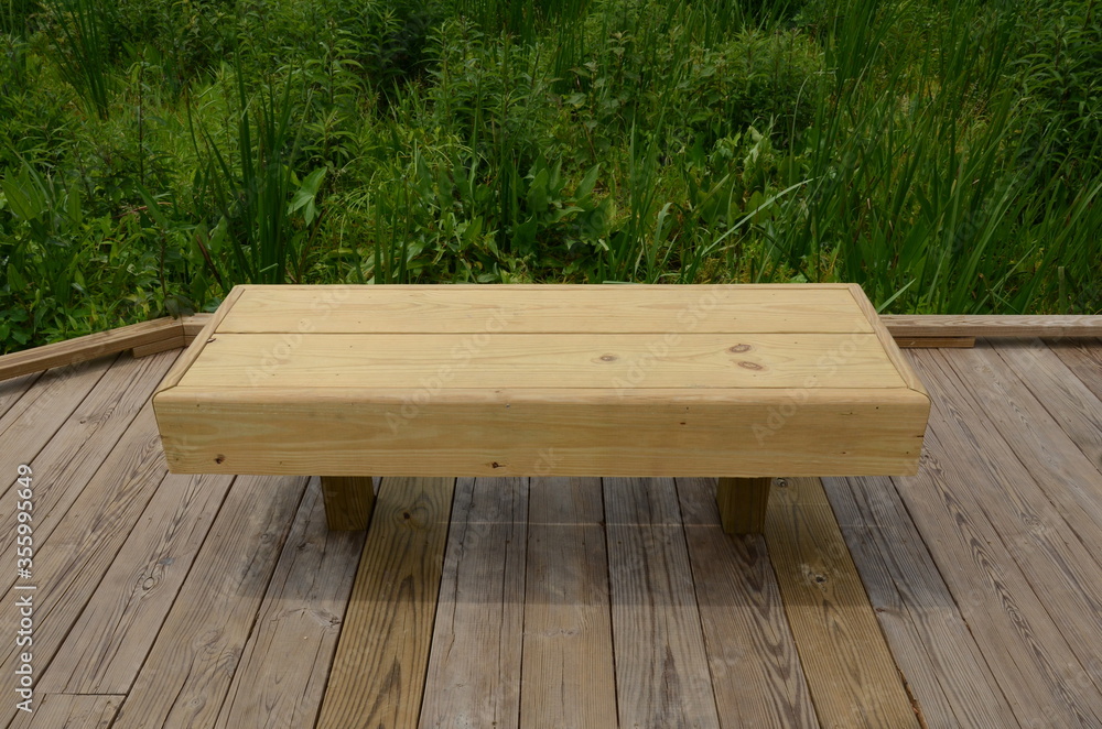 wood bench or seat on boardwalk with green plants