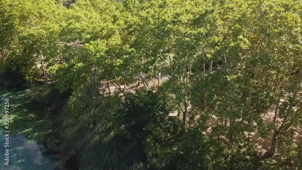 Aerial: Drone panning by green trees by turquoise lake on sunny day - Lake of Banyoles, Spain Aerial: Drone panning by green trees by turquoise lake on sunny day - Lake of Banyoles, Spain
