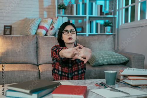 taiwanese young lady stretching arms forward to relax body in midnight. asian female student is heaving a sigh of relief for she finally gets her homework done.