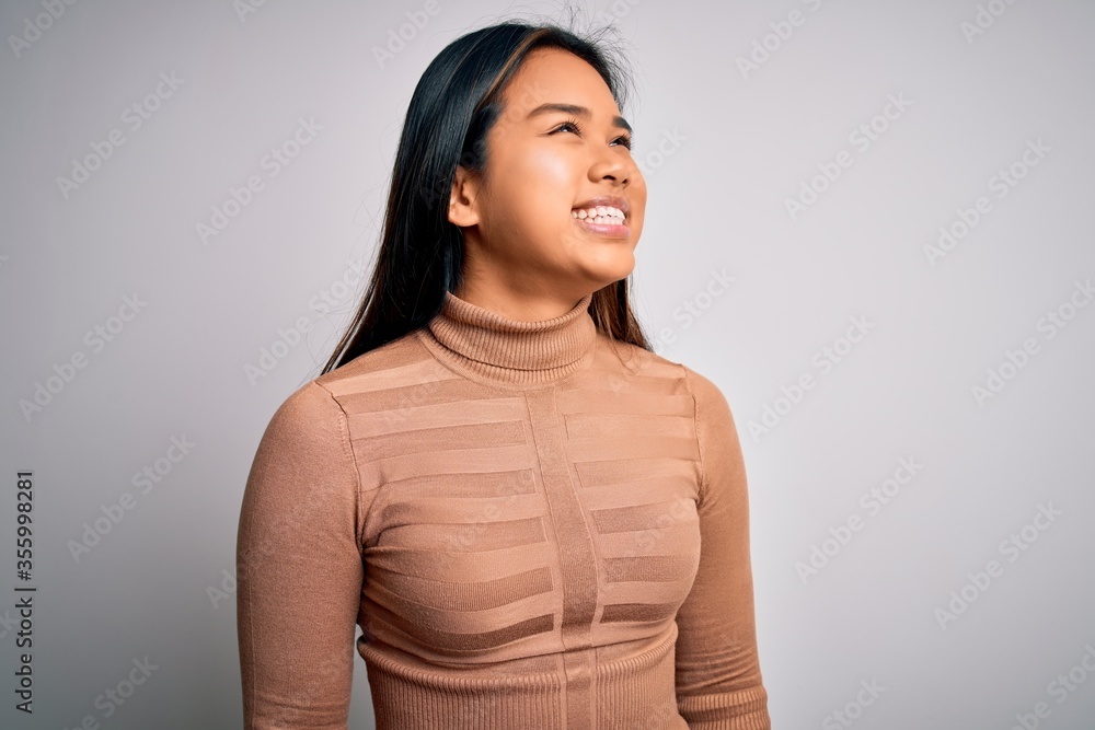 Young beautiful asian girl wearing casual turtleneck sweater standing over white background looking away to side with smile on face, natural expression. Laughing confident. Young beautiful asian girl wearing casual turtleneck sweater standing over white background looking away to side with smile on face, natural expression. Laughing confident.