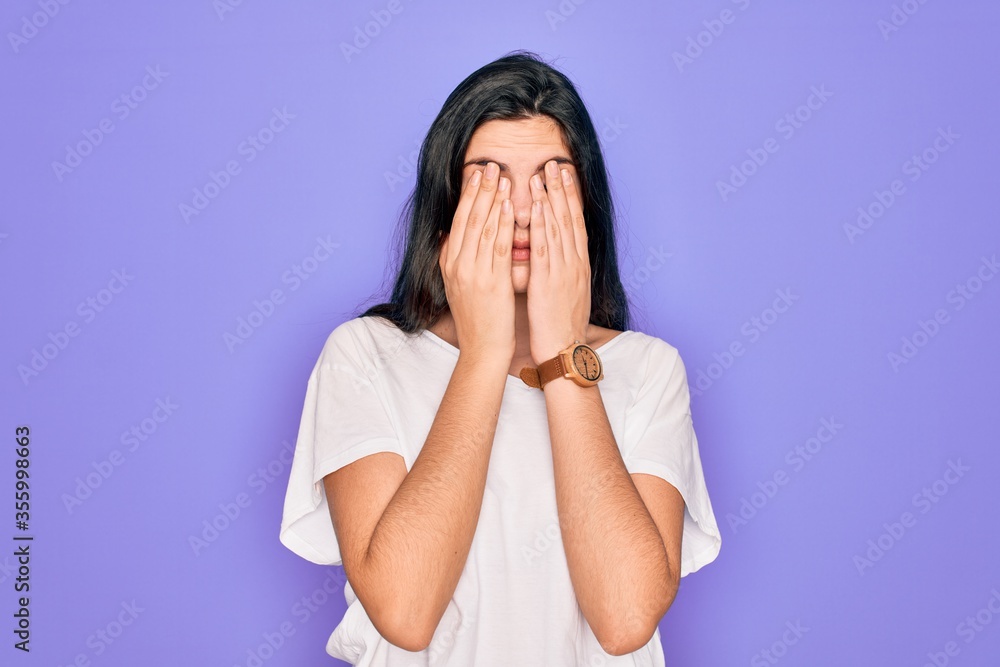 Young beautiful brunette woman wearing casual white t-shirt over purple background rubbing eyes for fatigue and headache, sleepy and tired expression. Vision problem Young beautiful brunette woman wearing casual white t-shirt over purple background rubbing eyes for fatigue and headache, sleepy and tired expression. Vision problem