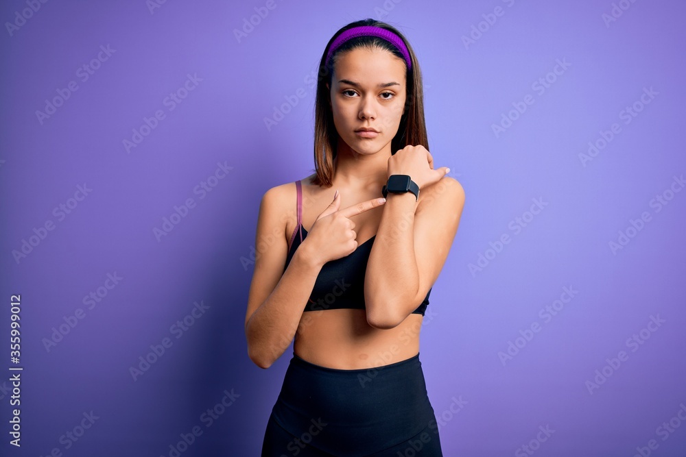Young beautiful sporty girl doing sport wearing sportswear over isolated purple background In hurry pointing to watch time, impatience, looking at the camera with relaxed expression Young beautiful sporty girl doing sport wearing sportswear over isolated purple background In hurry pointing to watch time, impatience, looking at the camera with relaxed expression
