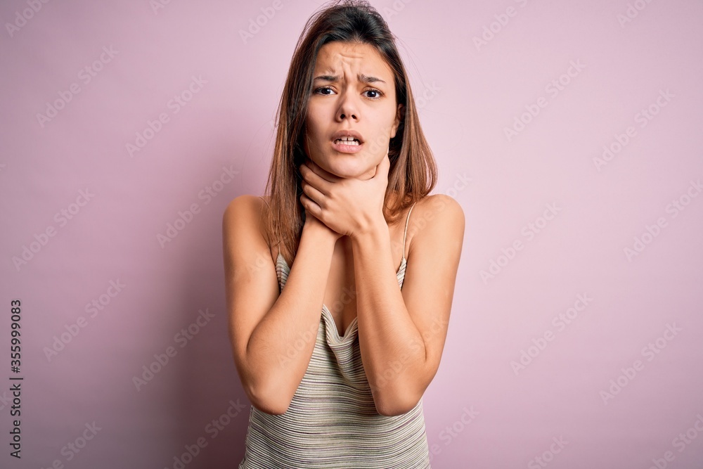 Young beautiful brunette girl wearing casual striped t-shirt over isolated pink background shouting and suffocate because painful strangle. Health problem. Asphyxiate and suicide concept. Young beautiful brunette girl wearing casual striped t-shirt over isolated pink background shouting and suffocate because painful strangle. Health problem. Asphyxiate and suicide concept.