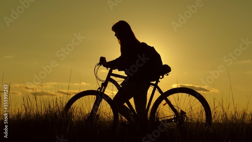 woman cyclist overcomes an obstacle. Healthy young woman tourist goes with bicycle along hillside, enjoying nature, fresh air. free girl travels with bicycle in sunset. adventure and travel concept.