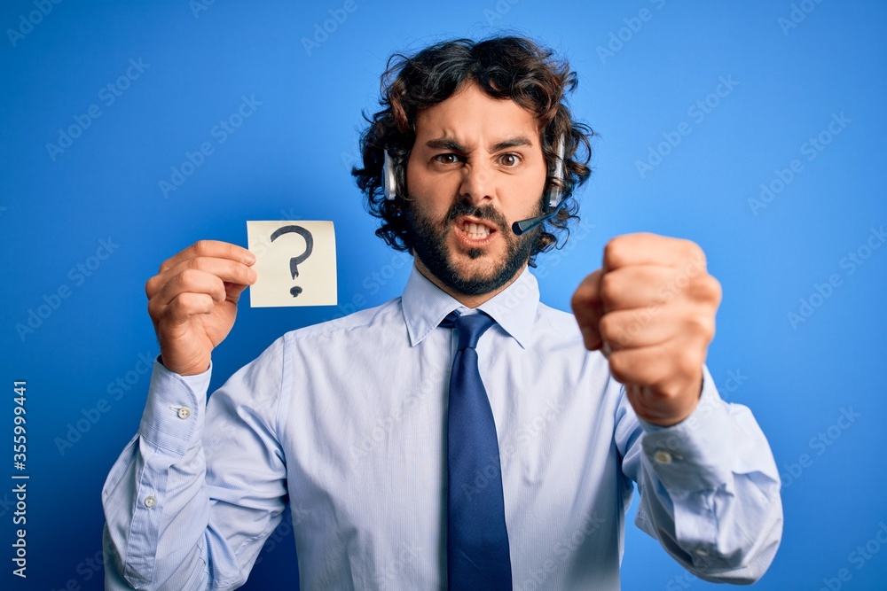 Young call center agent man with beard working using headset holding question mark reminder annoyed and frustrated shouting with anger, crazy and yelling with raised hand, anger concept Young call center agent man with beard working using headset holding question mark reminder annoyed and frustrated shouting with anger, crazy and yelling with raised hand, anger concept