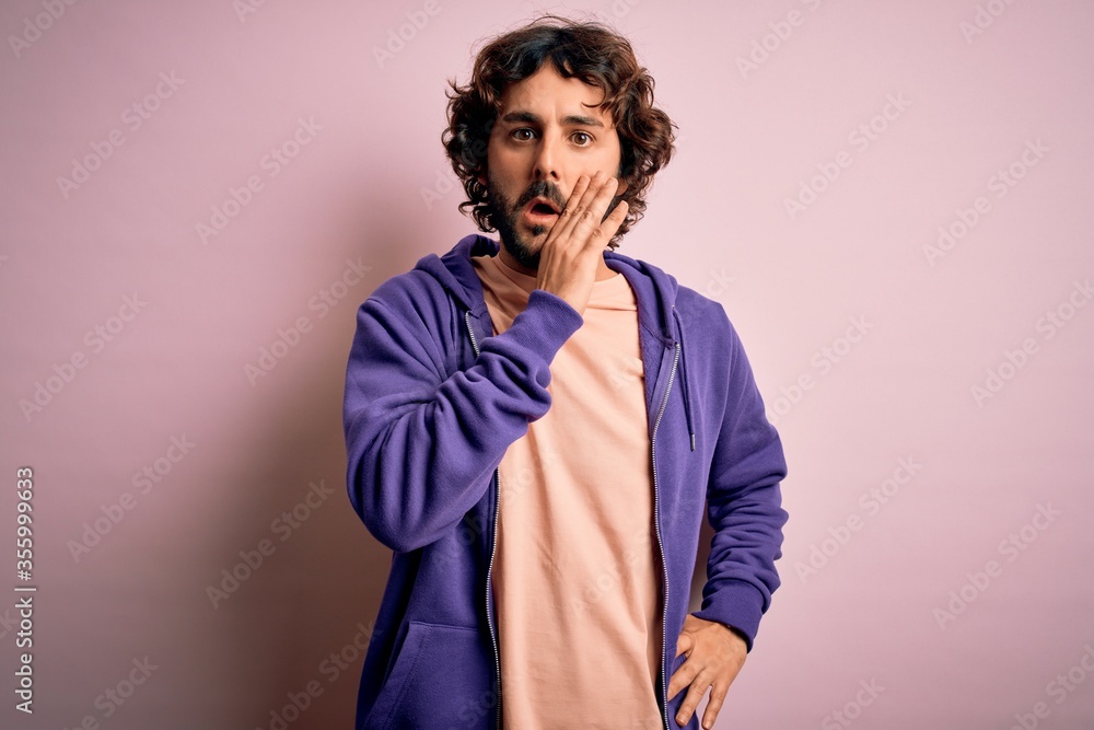 Young handsome sporty man with beard wearing casual sweatshirt over pink background hand on mouth telling secret rumor, whispering malicious talk conversation Young handsome sporty man with beard wearing casual sweatshirt over pink background hand on mouth telling secret rumor, whispering malicious talk conversation