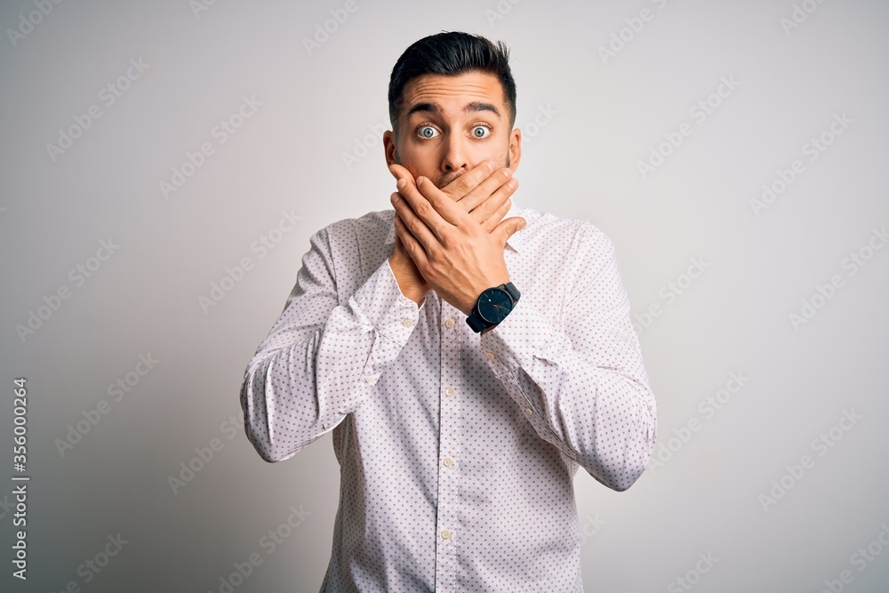 Young handsome man wearing elegant shirt standing over isolated white background shocked covering mouth with hands for mistake. Secret concept. Young handsome man wearing elegant shirt standing over isolated white background shocked covering mouth with hands for mistake. Secret concept.