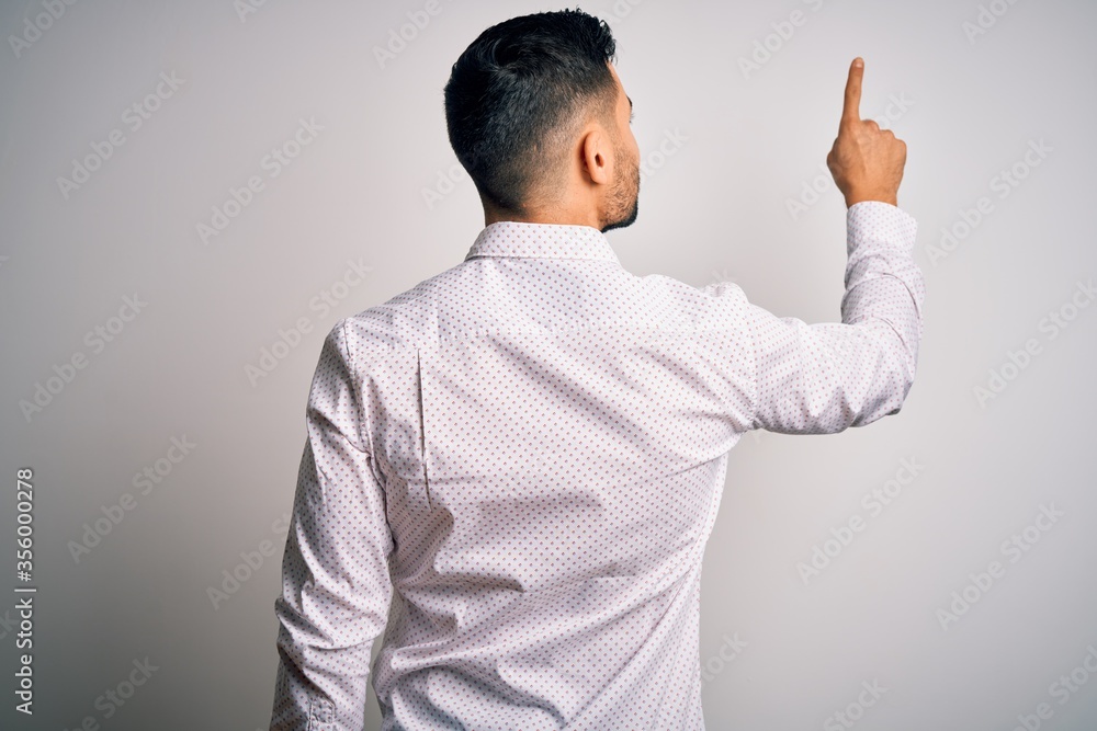 Young handsome man wearing elegant shirt standing over isolated white background Posing backwards pointing ahead with finger hand Young handsome man wearing elegant shirt standing over isolated white background Posing backwards pointing ahead with finger hand